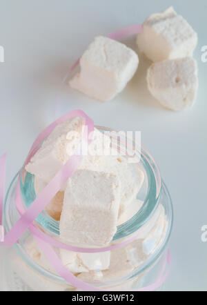 White marshmallows in glass jar on white table Stock Photo