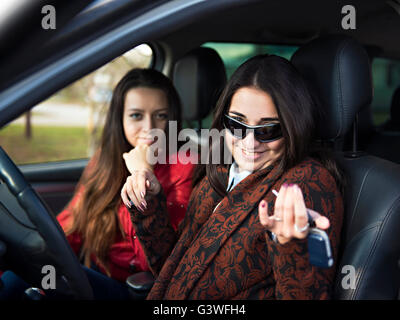 Two cute young smiling girl sitting in a car Stock Photo