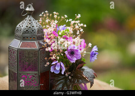 Garden style summer bouquet. Mix of lilac and purple anemone flowers, geranium flowers and heuchera or alumroot leaves. Bouquet Stock Photo