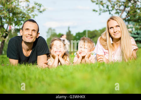 Portrait of happy parents with kids lying at the park Stock Photo