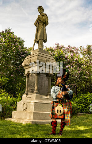 Scottish bagpiper dressed in traditional red and black tartan dress Stock Photo