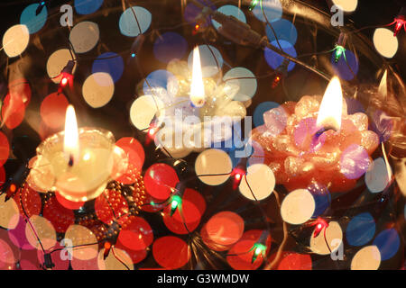 An abstract image of floating candles behind a wire mesh of colorful lights, during Diwali festival in India. Stock Photo