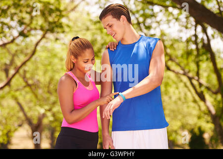 Young people doing sport activities, girl and friend running, man and woman using fit watch. Concept of eisure, health, recreati Stock Photo