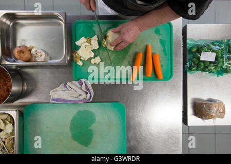 A cook cutting celery and carrots on a green cutting board. Stock Photo