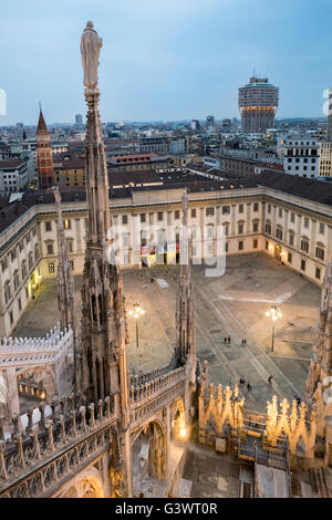 Italy, Milan Cathedral, Metropolitan Cathedral-Basilica of St Mary of the Nativity, Palazzo Reale and the square in front as seen from the roof of the Duomo, among the marble spire; bg.:  Bell Tower of the Church of Saint Gotthard of Hildesheim and The To Stock Photo
