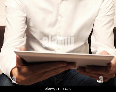 Businessman with a tablet computer reading an ebook, selective focus on man Stock Photo