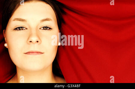 Beauty portrait of a beautiful teenage woman in front of a red curtain Stock Photo