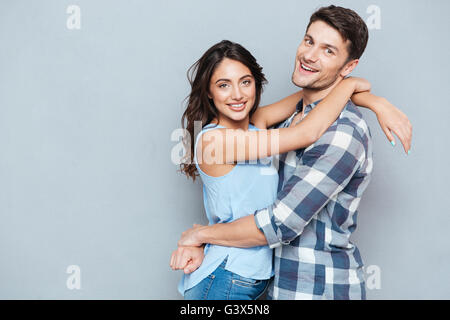 Casual young couple hugging each other and smiling at camera isolated on gray background Stock Photo