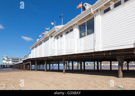 The Grand Pier on the seafront at Weston-Super-Mare at low tide with the sandy beach on a sunny day with blue sky. Stock Photo