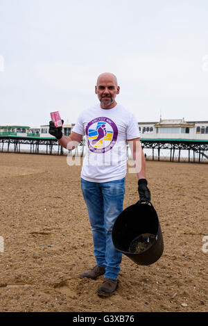 Man helping to clear litter and other rubbish from a sandy beach in Lytham St Anne's, Lancashire, UK Stock Photo