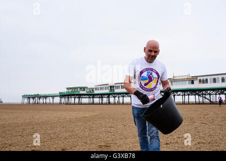 Man helping to clear litter and other rubbish from a sandy beach in Lytham St Anne's, Lancashire, UK Stock Photo