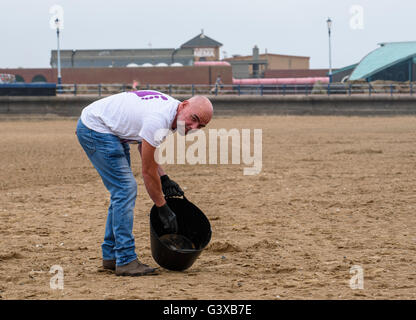 Man helping to clear litter and other rubbish from a sandy beach in Lytham St Anne's, Lancashire, UK Stock Photo