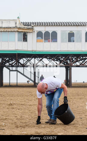 Man helping to clear litter and other rubbish from a sandy beach in Lytham St Anne's, Lancashire, UK Stock Photo