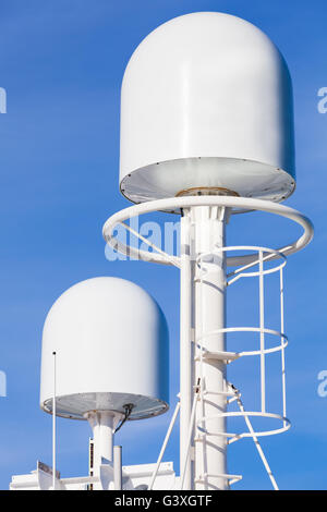 White GPS tracking antennas mounted on the top mast of modern passenger ferry ship Stock Photo