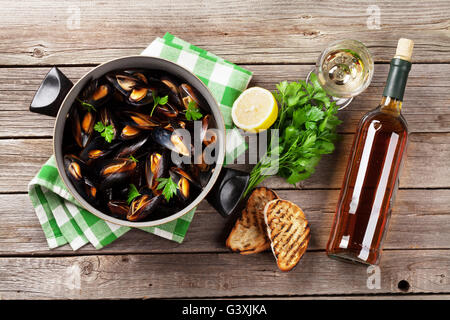 Mussels in copper pot and white wine on wooden table Stock Photo