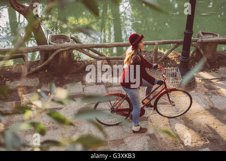 High angle view of happy girl riding bike at park in vintage urban fashion, nature scenery background.