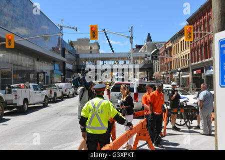 Ottawa, Canada – June 10, 2016: Local media reporter Leah Larocque,c, on site covering the story of the massive sinkhole that opened up on Rideau St two days before forcing the closure one of the busiest transit and shopping areas in the city. Stock Photo