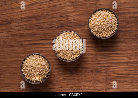 photo of millet in metal bowl on wooden table Stock Photo