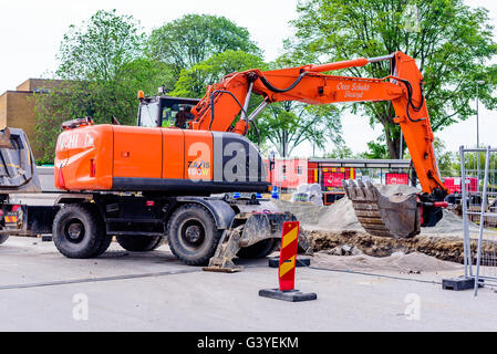 Karlskrona, Sweden - June 16, 2016: Orange Hitachi Zaxis 190W excavator digging out stones from a hole in a parking lot at Potth