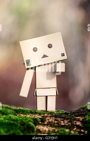 A Danbo Danboard fictional Robot Character standing on a branch covered in lichen Stock Photo