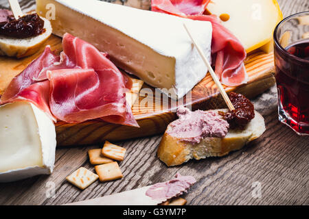 Antipasti platter with different meat and cheese products on  wooden board Stock Photo