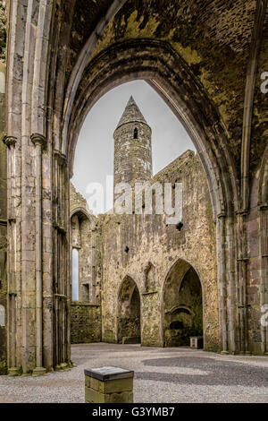 Round tower framed by an archway of a roofless cathedral at the Rock of Cashel (Kings & St. Patrick's Rock) Tipperary, Ireland. Stock Photo