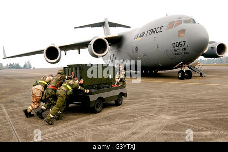 Airmen push a diesel generator in place after the C-17 Globemaster III lands. Stock Photo