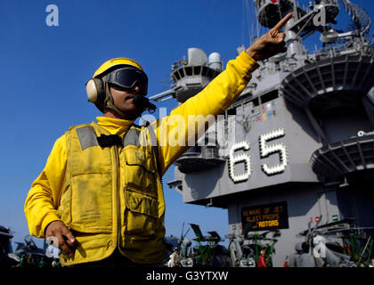 Chief Aviation Boatswain's Mate directs aircraft on the flight deck aboard USS Enterprise. Stock Photo