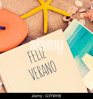 high-angle shot of a book with the text feliz verano, happy summer in Spanish written in its cover, an orange flip-flop, a starf Stock Photo