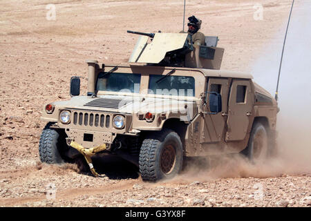 A humvee cruises up a dusty slope during a perimeter patrol. Stock Photo