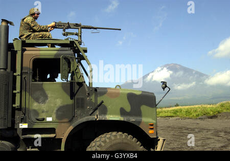 Soldier surveys the landscape with an M2 .50 caliber machine gun atop a seven-ton truck. Stock Photo