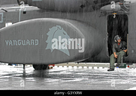 U.S. Navy Aviation Warfare Systems Operator waits in the rain on an MH-53E Sea Dragon.