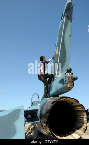 A technician performs post flight maintenance on a JASDF F-2 fighter aircraft. Stock Photo