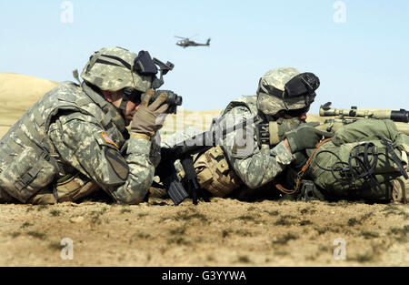 Two U.S. Army soldiers using binoculars and a riflescope to watch for insurgents near the Syrian border in Iraq. Stock Photo