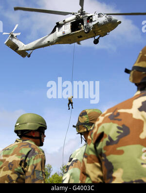 Airmen from the air assault team watching as a fellow team member rappels from an HH-60 Pave Hawk helicopter. Stock Photo