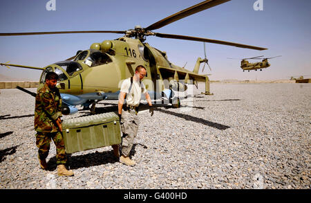 U.S. Air Force soldier helps an Afghan airman carry ammunition to a Mi-35 Hip helicopter.