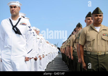 U.S. Marines and Sailors stand at attention before manning the rails aboard aircraft carrier USS Ronald Reagan. Stock Photo