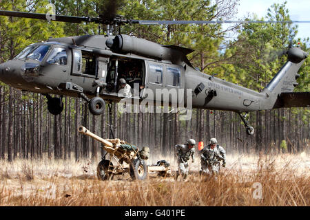 Paratroopers connect a howitzer to a UH-60M Black Hawk helicopter. Stock Photo