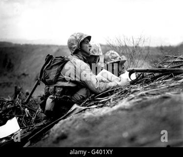 Soldiers locate enemy position on a map while positioned behind a berm. Stock Photo