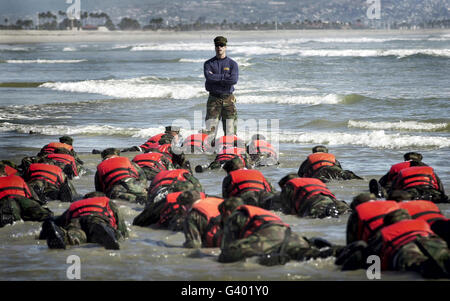 A Navy SEAL instructor assists students during a Hell Week surf drill evolution. Stock Photo