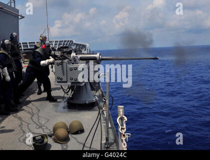 Gunner fires a Mark 38 machine gun aboard USS Frank Cable. Stock Photo