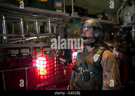 A loadmaster waits to release a load of bundles from the back of a C-130 Hercules. Stock Photo