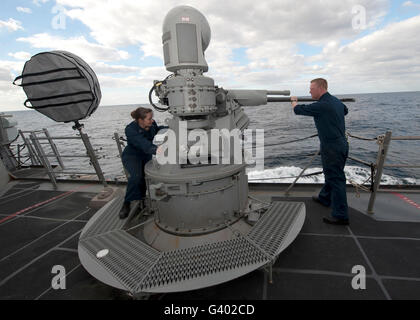 Sailors conduct maintenance on the MK38 MOD-2 25mm machine gun system. Stock Photo