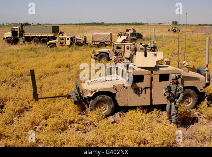 U.S. Army soldiers provide security from their M1114 humvees.