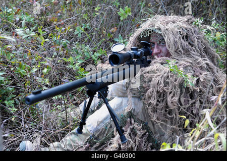Sniper dressed in a ghillie suit. Stock Photo