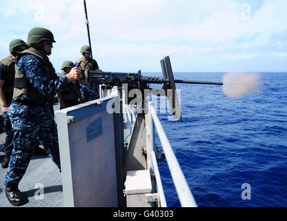 Master-at-Arms fires a .50-caliber machine gun aboard USS Tortuga. Stock Photo