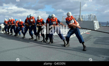 Line handlers heave around aboard USS William P. Lawrence. Stock Photo