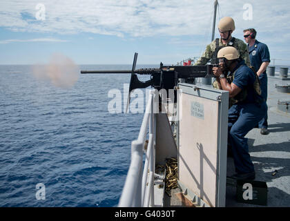 Sailor fires a .50 caliber machine gun aboard USS Tortuga. Stock Photo