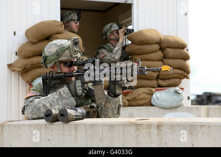 U.S. Army soldier looks down the scope of his M4 assault rifle. Stock Photo