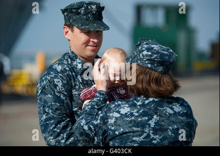 Navy Counselor hands his daughter to his wife before departure. Stock Photo